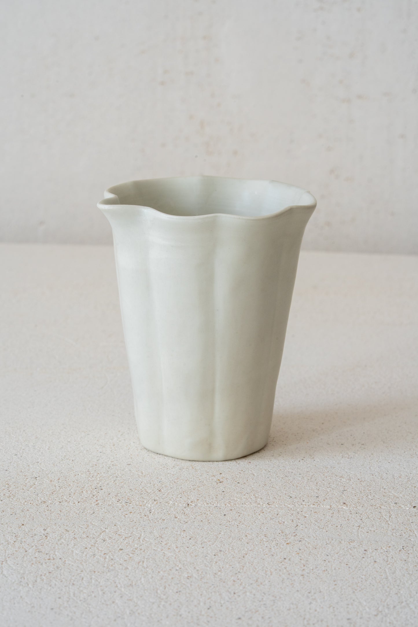 A white-glazed pitcher by Tomoko Sakai. A soft matte glaze settles over the gently fluted form, while the subtle curves give the piece a quiet sense of movement. Designed for Gongfu-style tea, it pours with ease and sits lightly on the table.