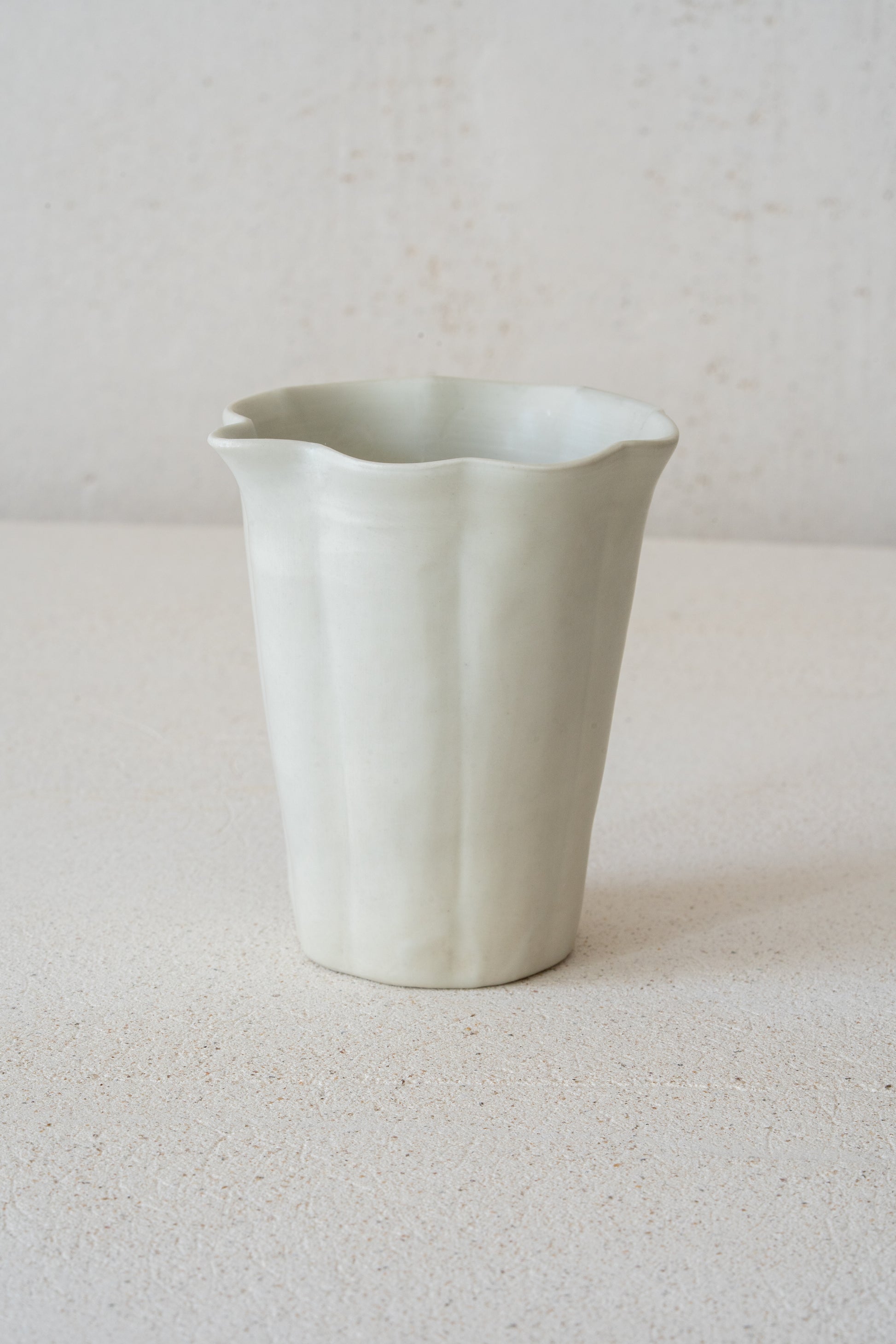 A white-glazed pitcher by Tomoko Sakai. A soft matte glaze settles over the gently fluted form, while the subtle curves give the piece a quiet sense of movement. Designed for Gongfu-style tea, it pours with ease and sits lightly on the table.